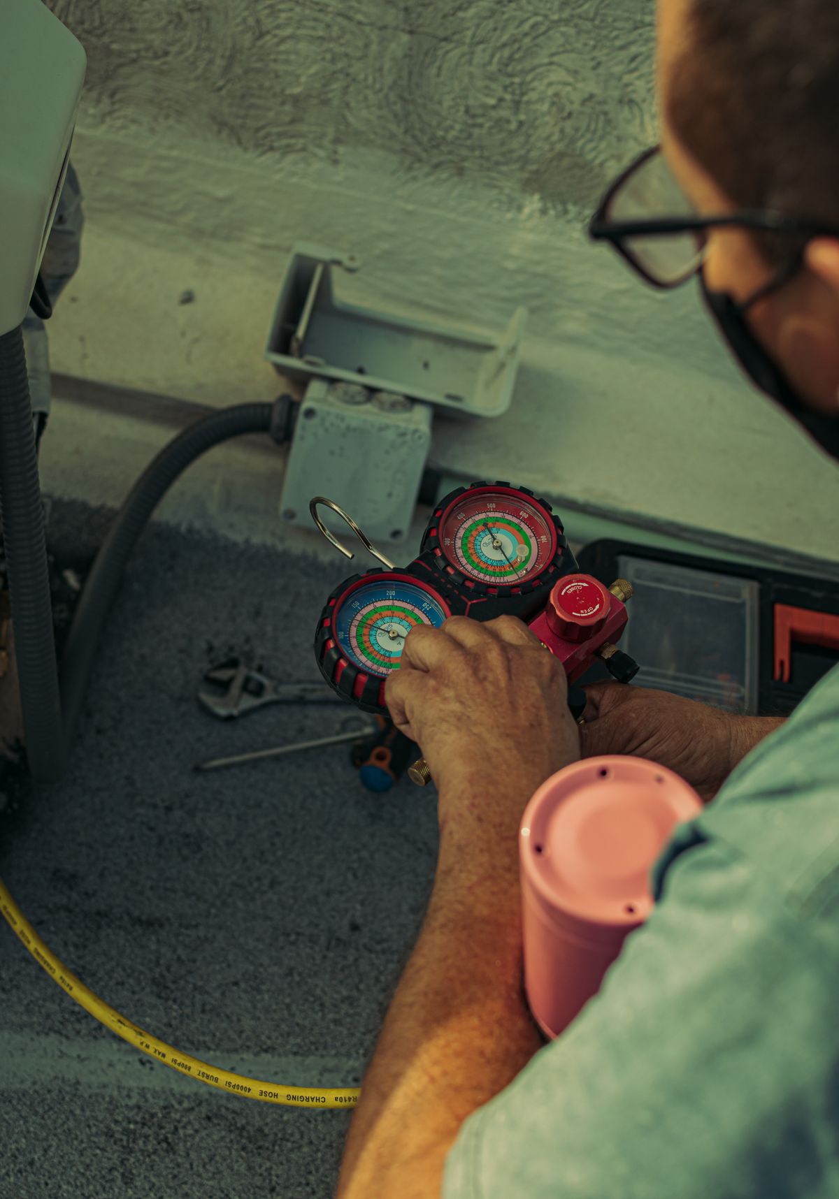 Technician adjusting refrigerant manifold gauges during an HVAC inspection